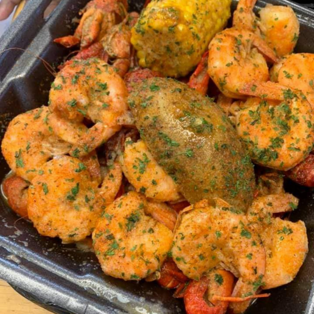 Seasoned shrimp and potato meal in a black to-go container