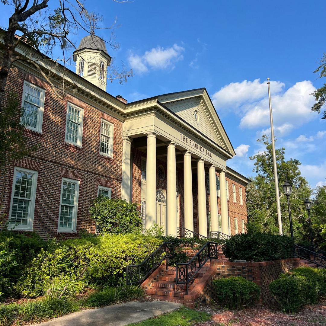 Angled photo of The Florida Bar, a brick building, with manicured greenery in the front, and a blue sky behind the building.