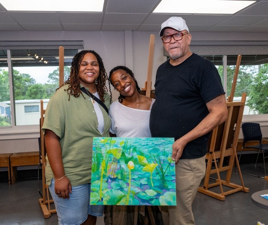 three people holding a greenery painting