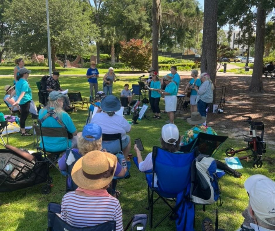 A group of people outside watching people put on a show with their instruments