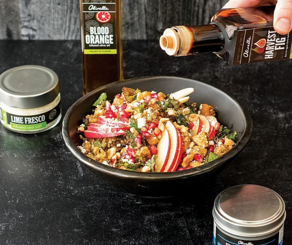 A fresh salad topped with Browns Kitchen's Olivelle dressing, accompanied by a selection of seasonings and infused olive oil