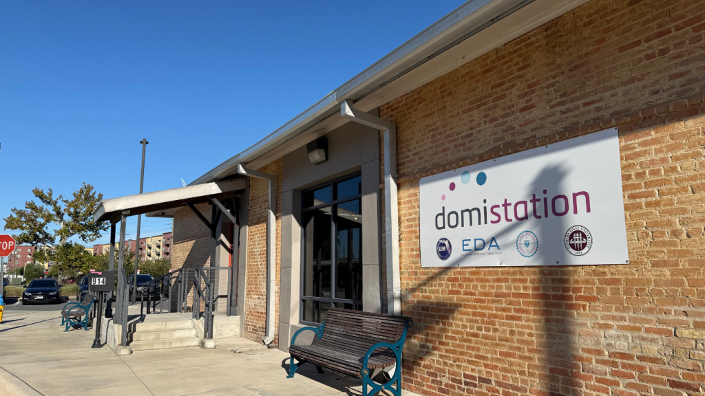 Brick exterior of Domi Station building, with sign at entrance