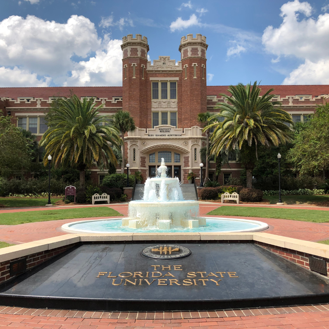 Red Brick Westcott Building with twin towers and a fountain out front on a blue sky day